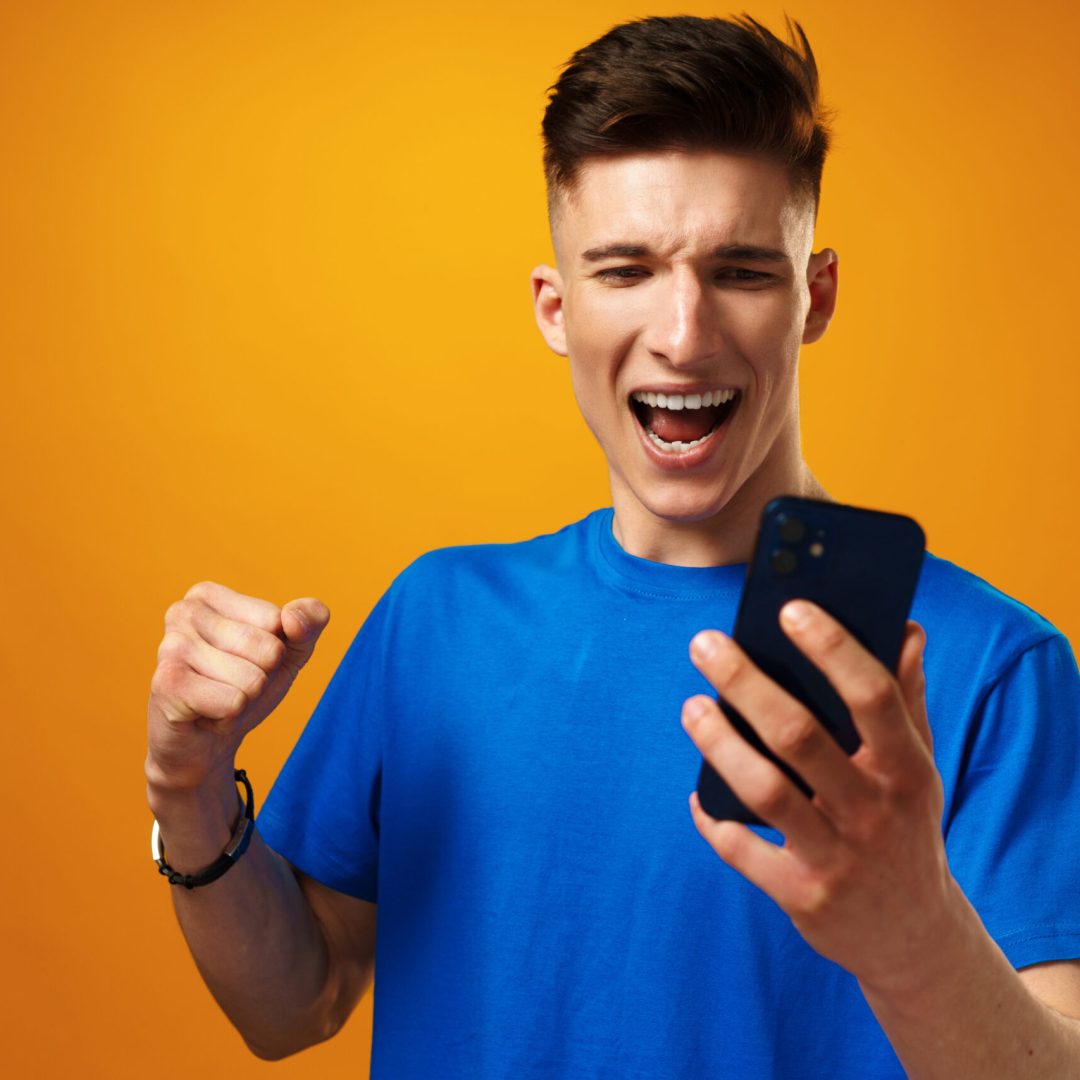 Young man using smartphone against yellow background, close up